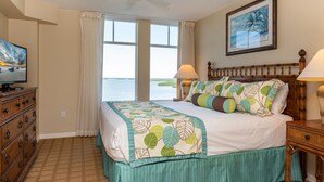 A bedroom with a bed, a television, a ceiling fan, a window with curtains, and a painting on the wall. - Lovers Key Resort (Fort Myers Beach)
