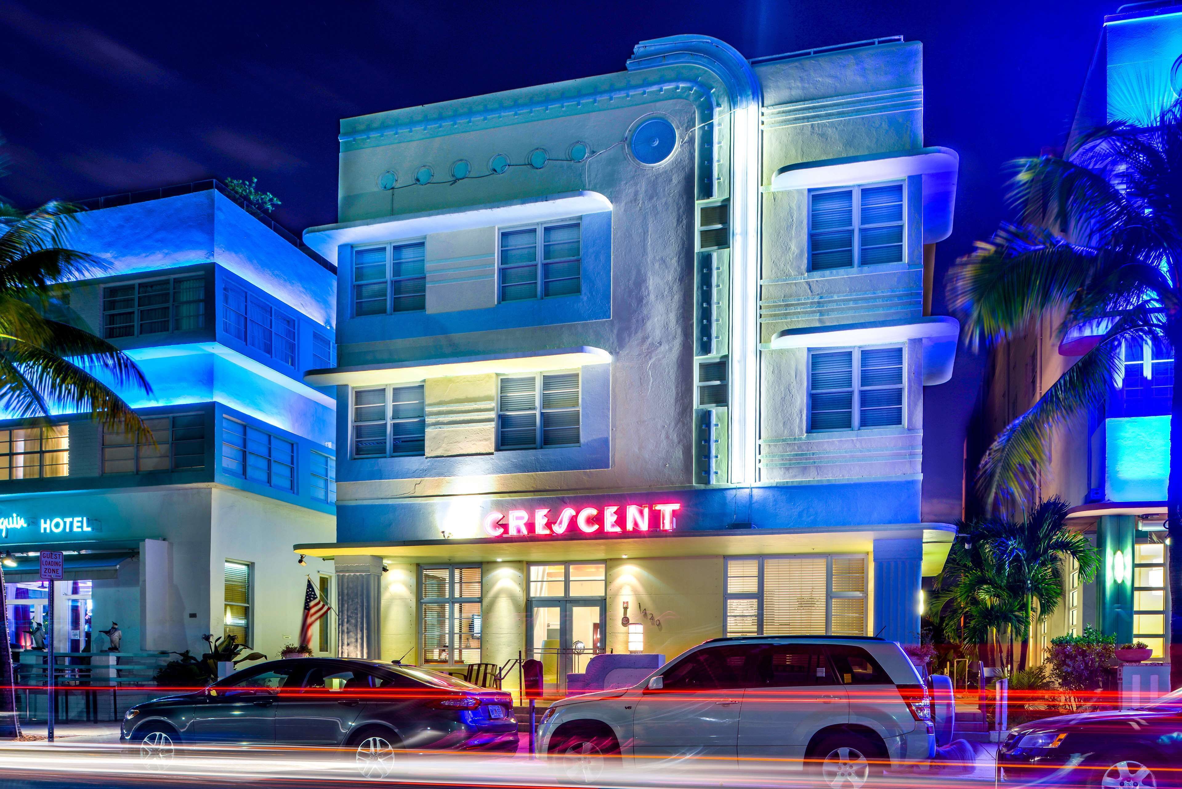 Ein Hotel namens 'Crescent' mit modernem Design, ausgestattet mit einer auffälligen Neonreklame, mehreren Etagen und einem Parkplatz mit Autos.