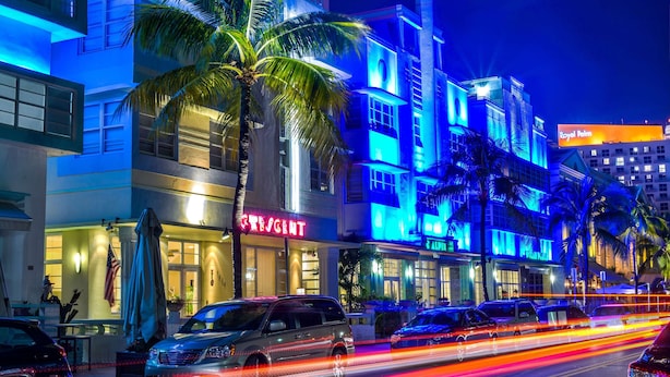 A hotel with a prominent 'RESIDENT' sign, palm trees, and a 'Royal Palm' sign in the background. - Hilton Vacation Club Crescent on South Beach Miami (Miami Beach)