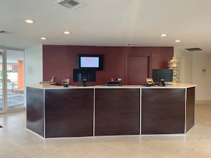 A reception desk with a flat-screen TV, a cash register, and a phone. - Red Roof Inn Tucson Downtown – University (Tucson)