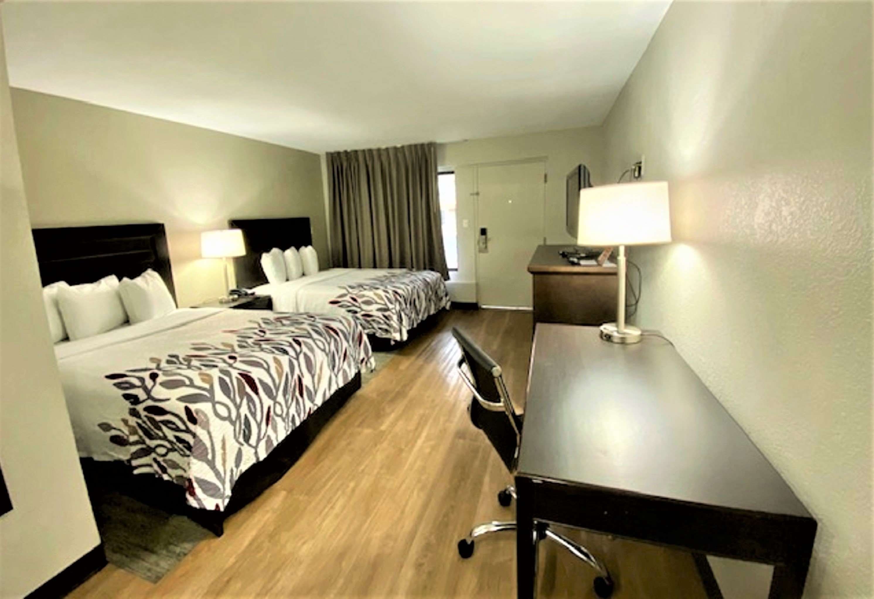 A hotel room with two beds, a desk, and a chair.