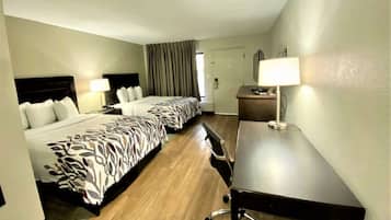 A hotel room with two beds, a desk, and a chair.