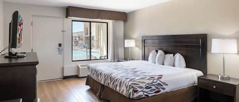 Habitación de hotel con una cama grande, un escritorio, un televisor y una ventana con vistas a edificios.
