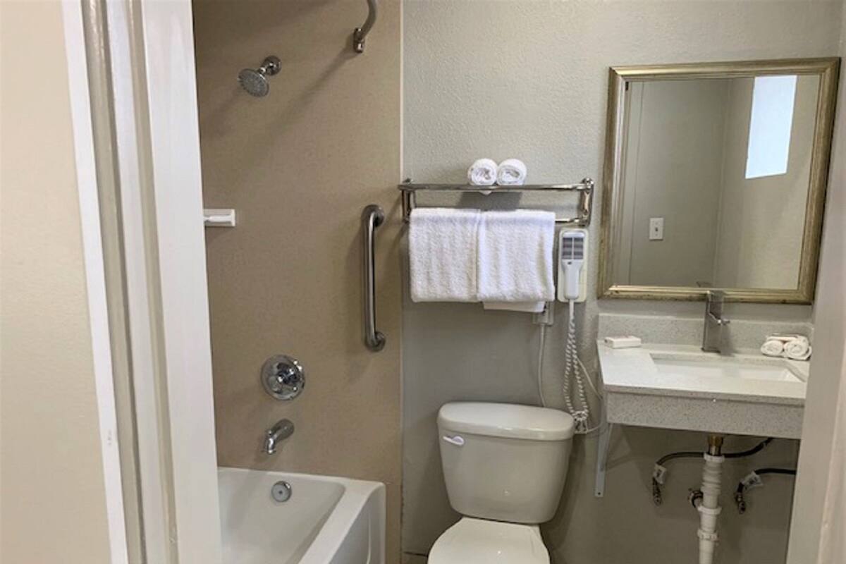 A bathroom with a bathtub, toilet, and sink. There is a towel rack with towels and a mirror above the sink.