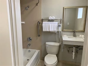 A bathroom with a bathtub, toilet, and sink. There is a towel rack with towels and a mirror above the sink. - Red Roof Inn Tucson Downtown – University (Tucson)