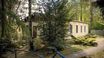 Guests can stroll along the winding pathway to a serene retreat with lush greenery and a simple, functional building.
