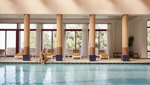 An indoor swimming pool with clear glass ceilings, large windows, and sun loungers along the poolside. - Grand Mercure Petra (Wadi Musa)