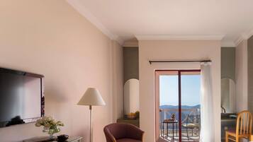 A hotel room with a bed, a desk with a lamp, a chair, and a view of the outdoors.
