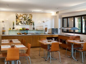 A modern dining area with wooden tables and chairs, a buffet counter with various food items, and a large abstract painting on the wall. - TH La Florida (Madrid)