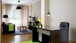 A modern living room with a glass desk, a sofa, a coffee table, and a TV. - TH La Florida (Madrid)