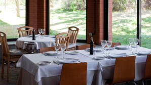 A restaurant with tables set for dining, featuring a view of a garden through large windows. - TH La Florida (Madrid)