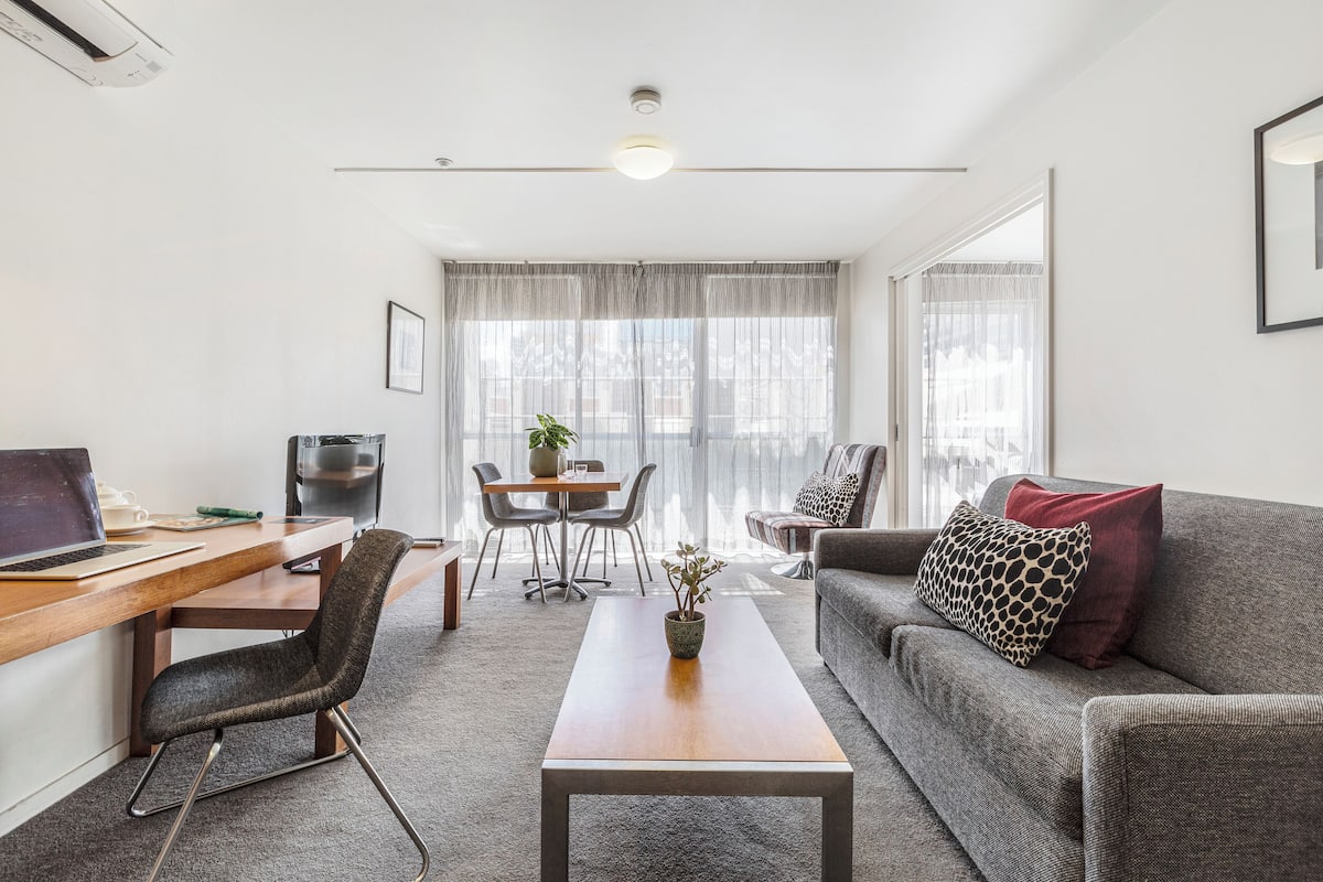 A modern living room with a wooden desk, a grey sofa, and a coffee table.