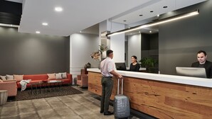 A modern hotel lobby with a reception desk, a red sofa, and a wooden reception area. - Punthill Little Bourke (Melbourne)