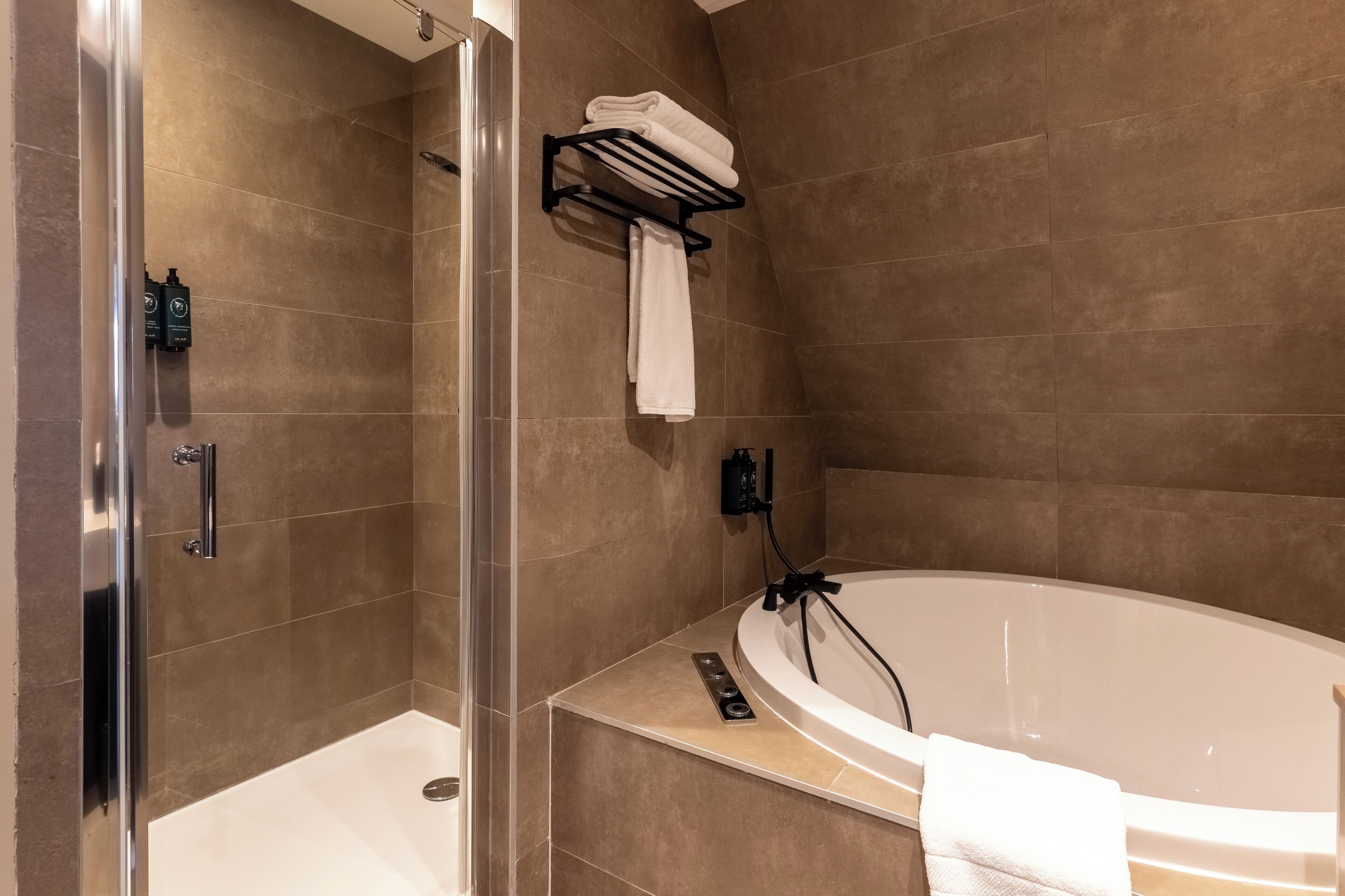 Un baño moderno con ducha a nivel, bañera y un perchero para toallas.