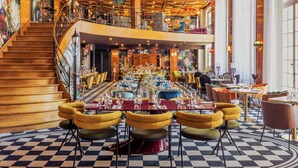 A spacious restaurant with a checkered floor, multiple dining tables, and a staircase leading to an upper level. - Château Jeanne & the Forest - Château de Montvillargenne (Gouvieux)