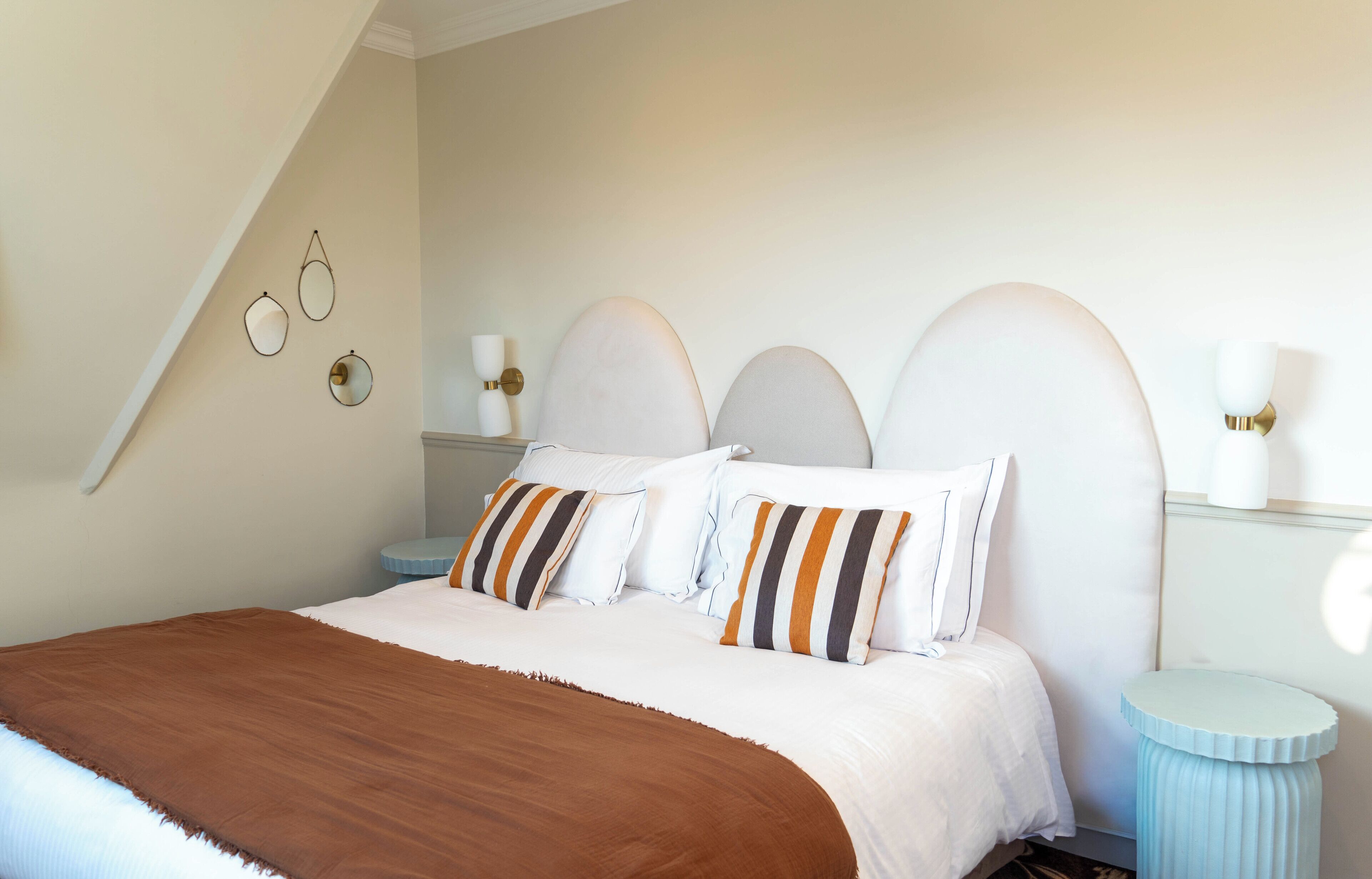 A bedroom with a bed, pillows, a nightstand, and wall sconces.