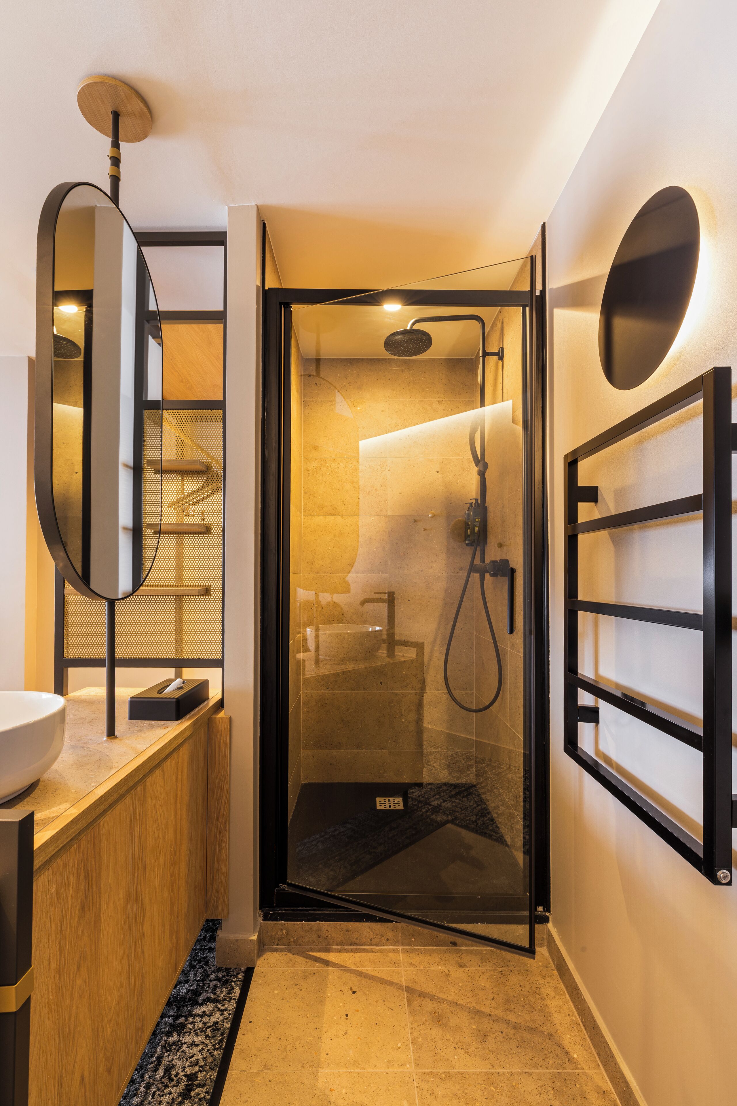 A modern bathroom with a glass-enclosed shower, a wooden vanity, a large mirror, and a wall-mounted towel rack.