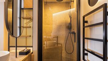 A modern bathroom with a glass-enclosed shower, a wooden vanity, a large mirror, and a wall-mounted towel rack.