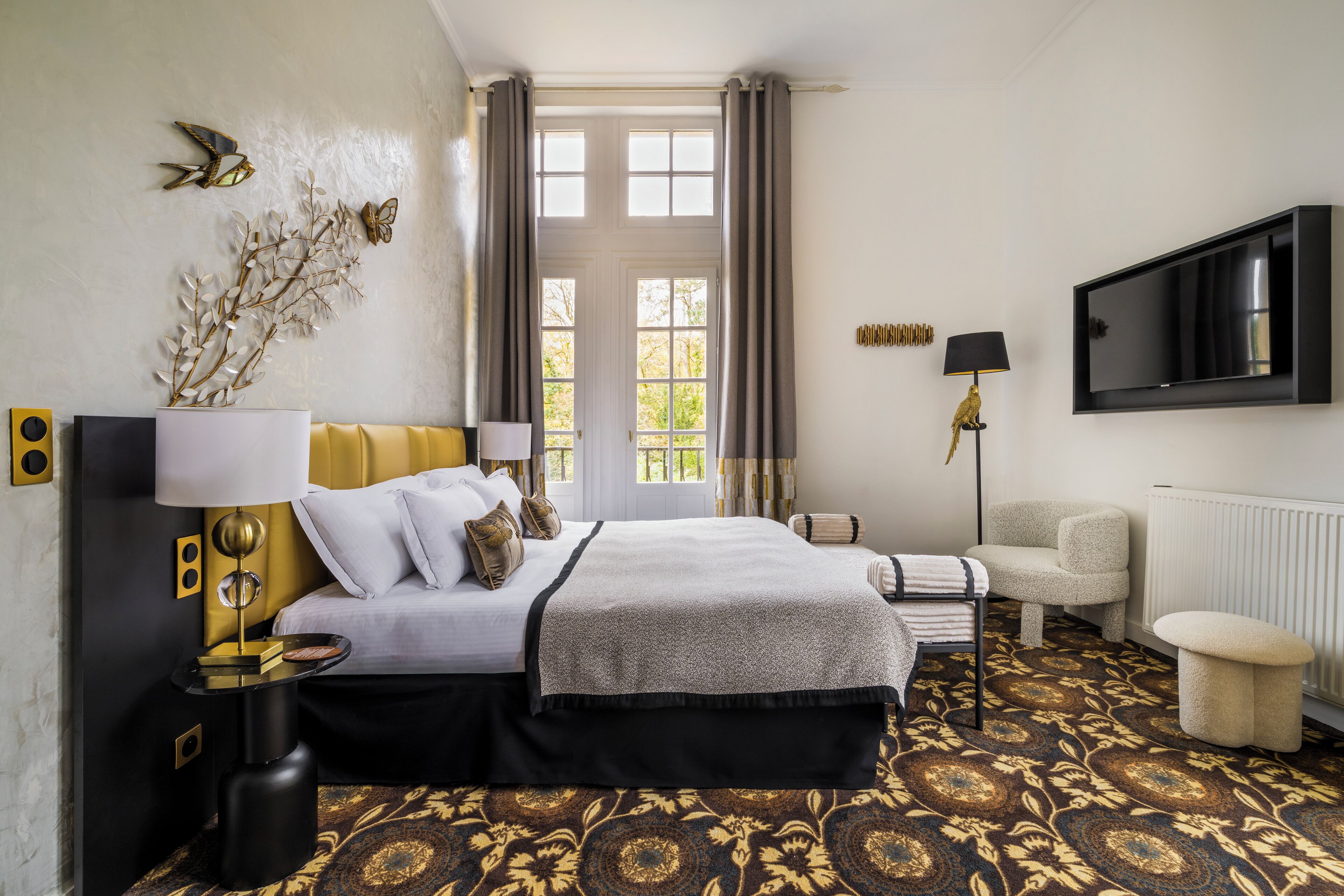 Una camera d'albergo con un letto, un comodino, una lampada e una televisione appesa al muro.