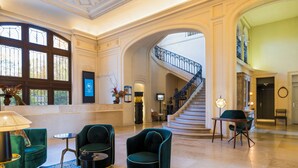 A spacious lobby with a grand staircase, elegant green upholstered chairs, and a marble floor. - Château Jeanne & the Forest - Château de Montvillargenne (Gouvieux)