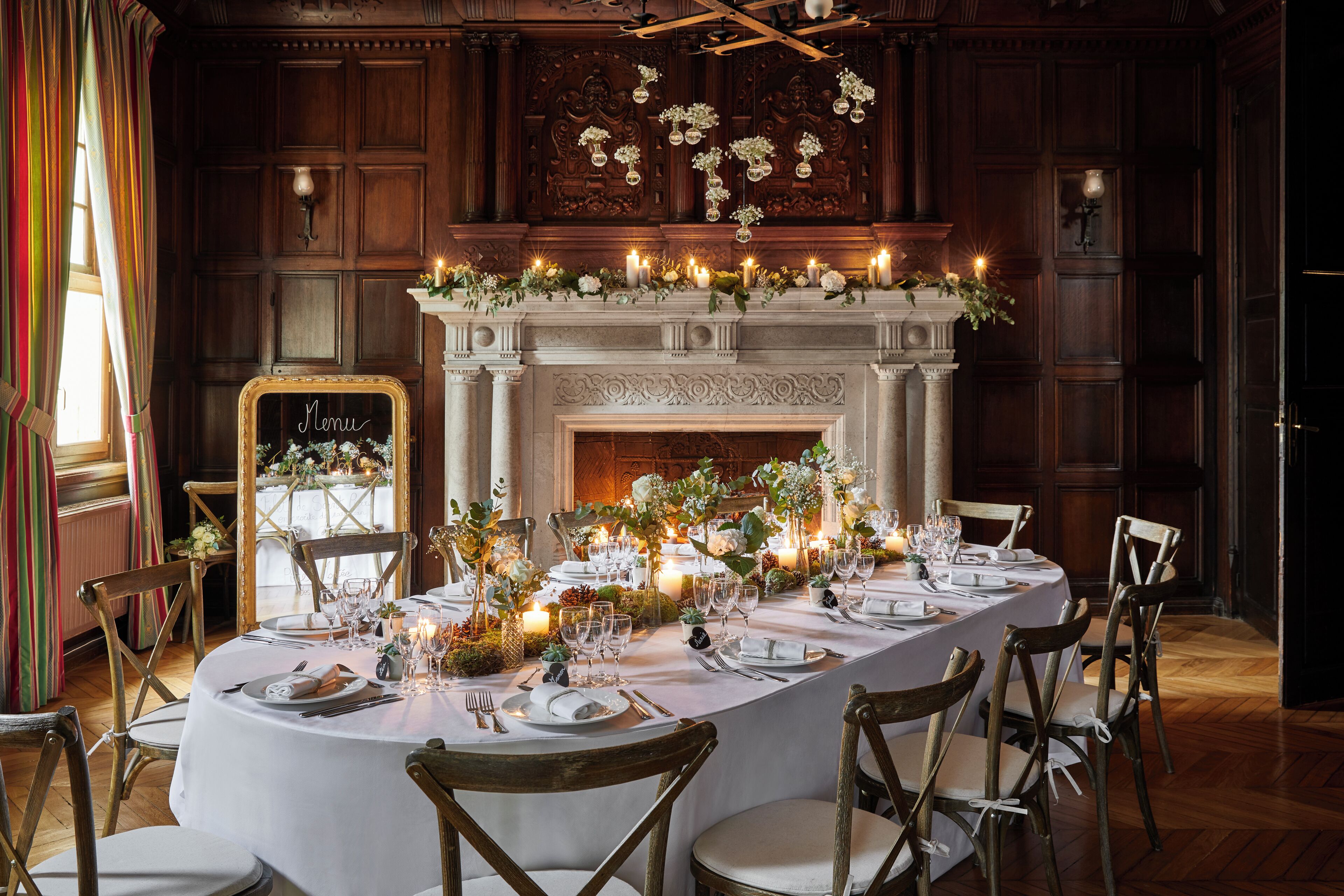 A formal dining room with a long table set for a meal, surrounded by wooden chairs.