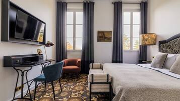 Een hotelkamer met een bed, een bureau, een stoel, een televisie en een raam met gordijnen.