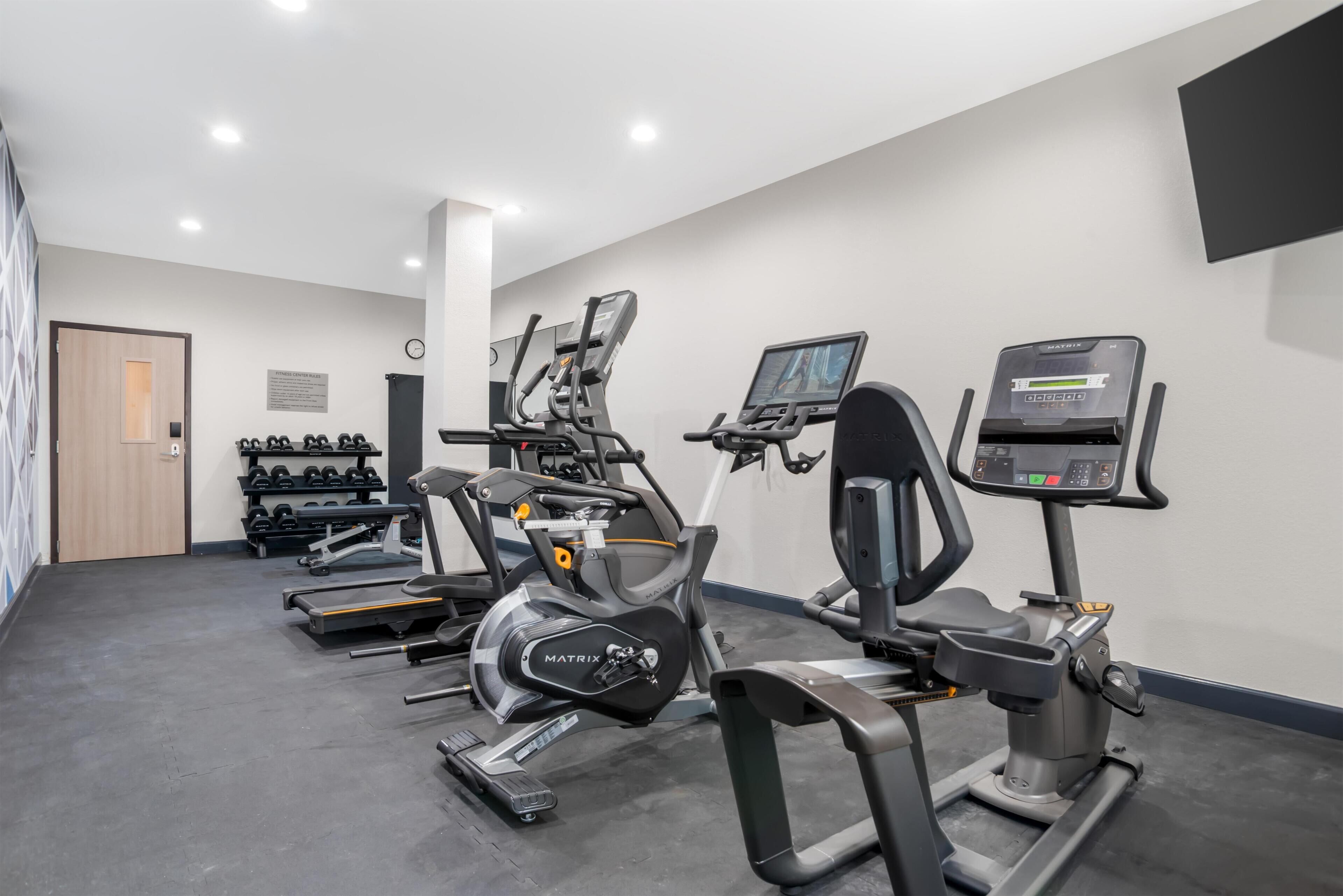 A gym with treadmills, elliptical machines, and free weights.