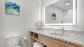 A bathroom with a white toilet, a sink with a mirror, and a shower.
