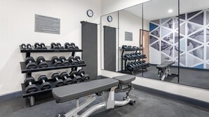 Ein Fitnessraum mit Hanteln, einer Langhantelbank und einem großen Spiegel.