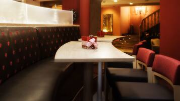 Un interior de restaurante con una zona de asientos en cabinas, una mesa con servilleta a cuadros rojos y una escalera que sube a un nivel superior.