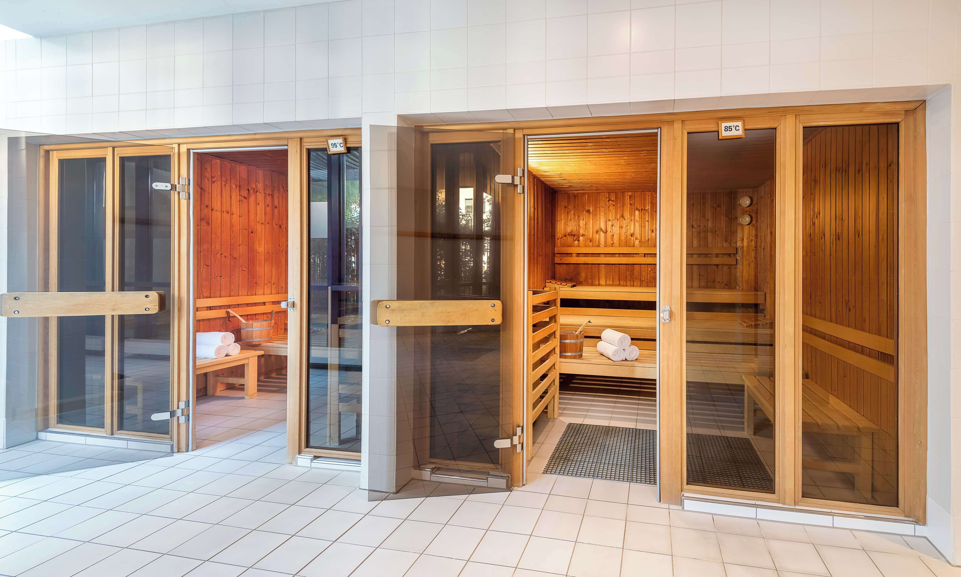 A sauna area with wooden benches and benches, a bench with towels, and a bench with a towel and a glass of water.