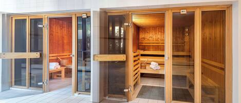 A sauna area with wooden benches and benches, a bench with towels, and a bench with a towel and a glass of water.