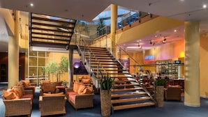 Een ruime lobby met een centrale trap, comfortabele zithoeken en een bar.