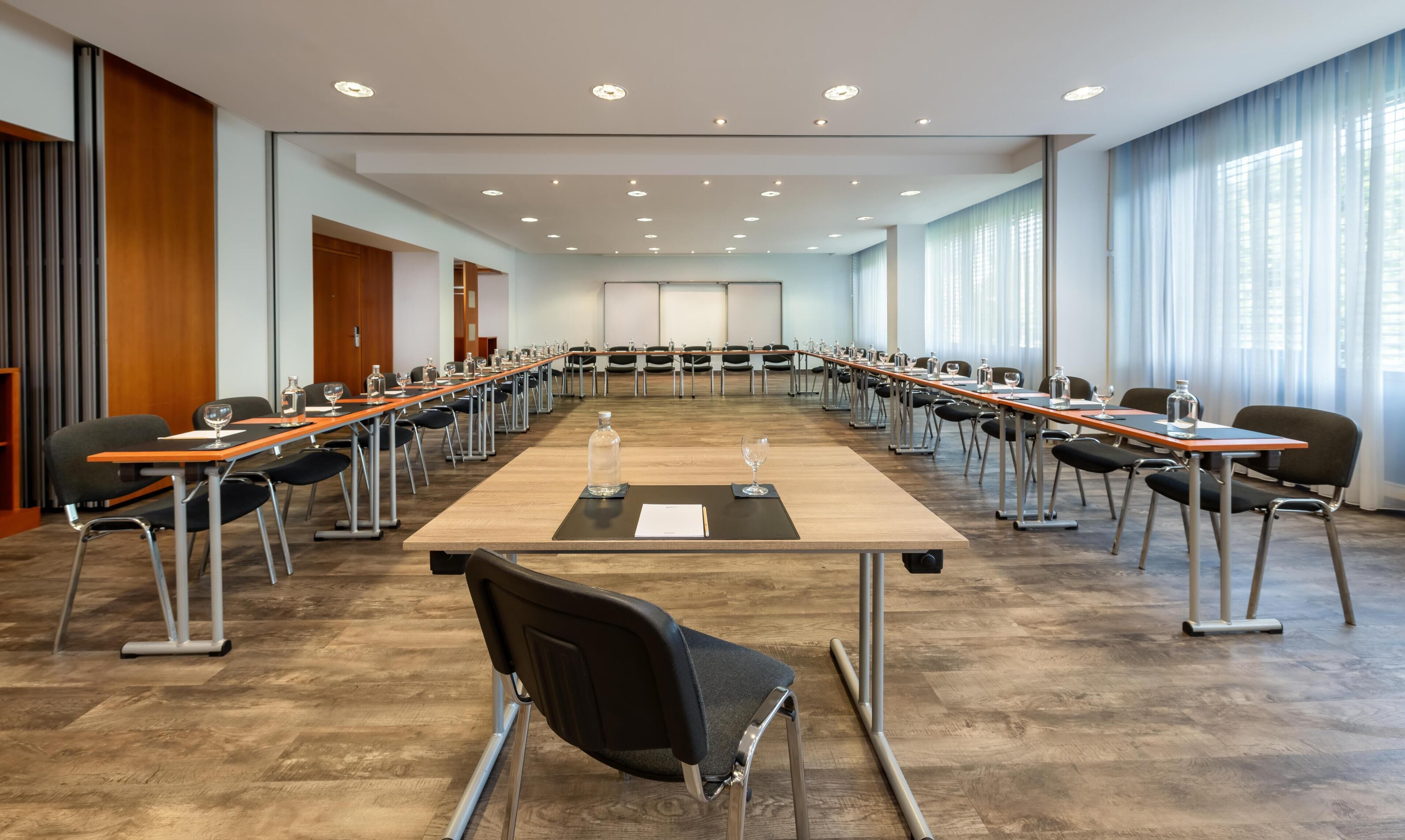 A conference room with a long table, chairs, and a projector screen.