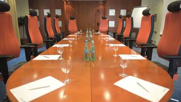 Ein Konferenzraum mit langem Tisch, orangefarbenen Stühlen, Wasserflaschen und Gläsern.