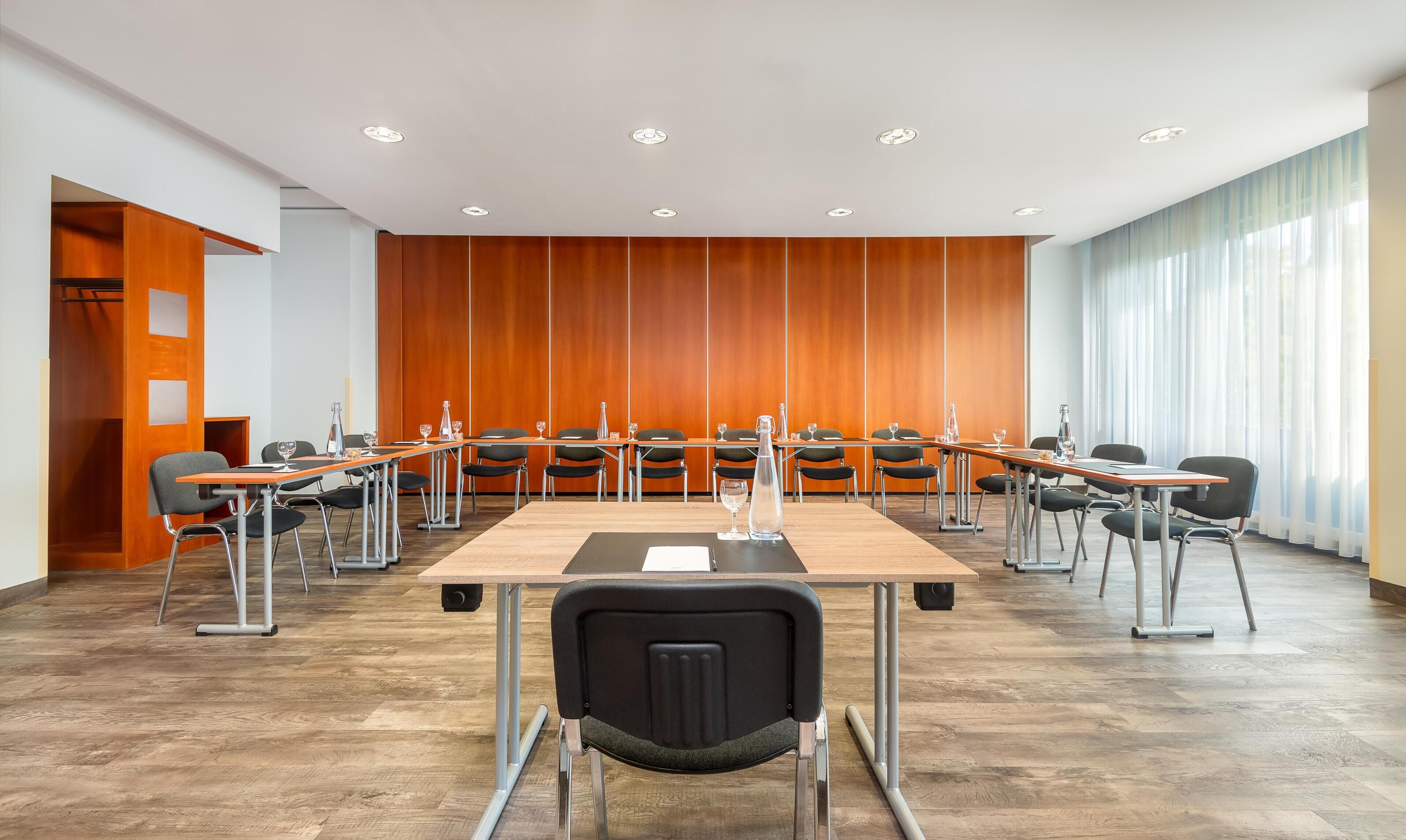 Uma sala de conferências com uma mesa comprida, cadeiras e parede revestida de madeira.