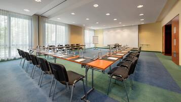 Un salón de conferencias con una larga mesa, sillas y una pantalla para proyector.