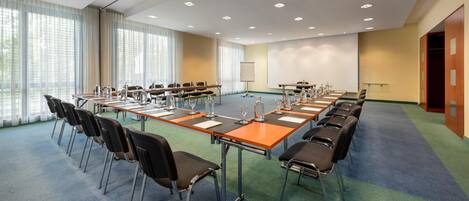 Une salle de conférence équipée d’une longue table, de chaises et d’un écran de projection.