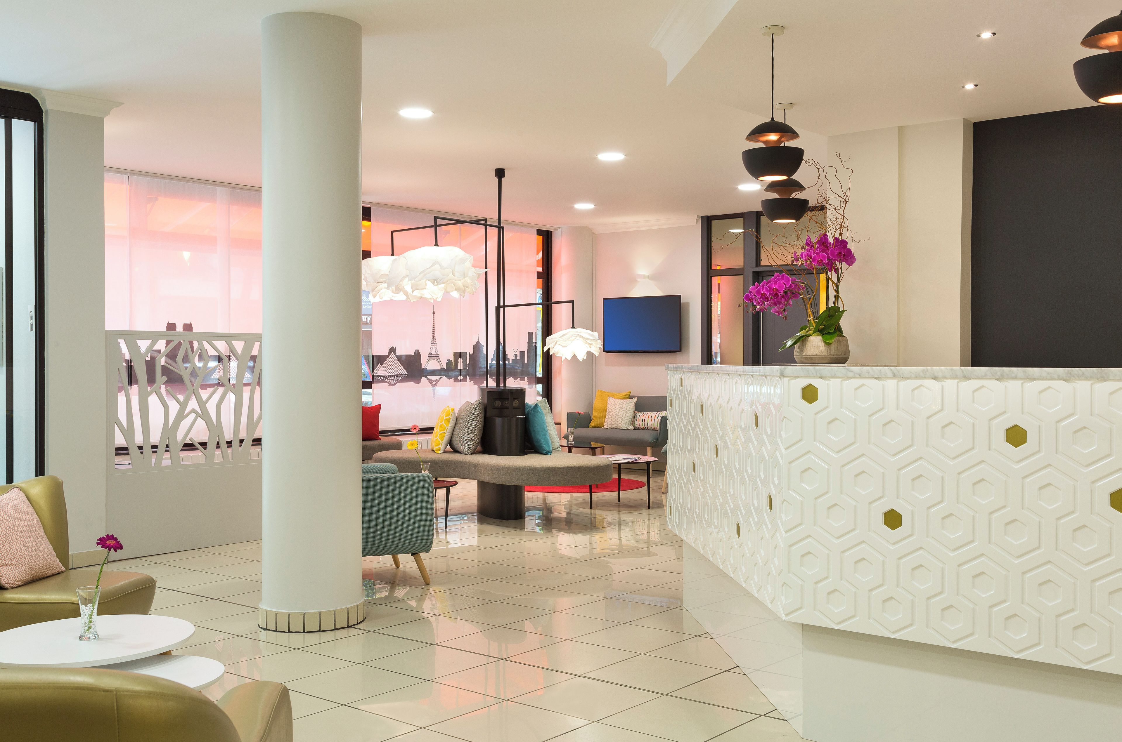 A modern hotel lobby with a reception desk, seating area, and a cityscape view.