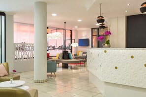 Un hall d’hôtel moderne avec un comptoir d’accueil, un espace salon et une vue sur le paysage urbain.