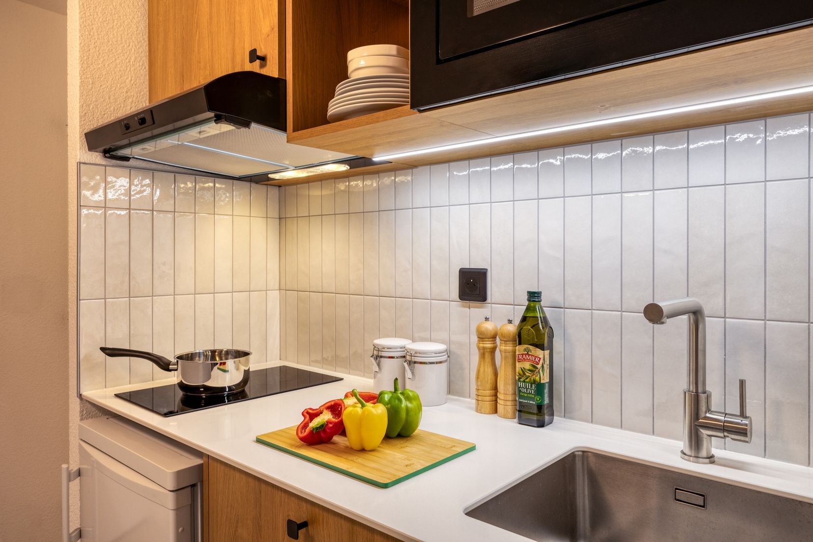 Een moderne keuken met een fornuis, spoelbak en een snijplank met groenten.