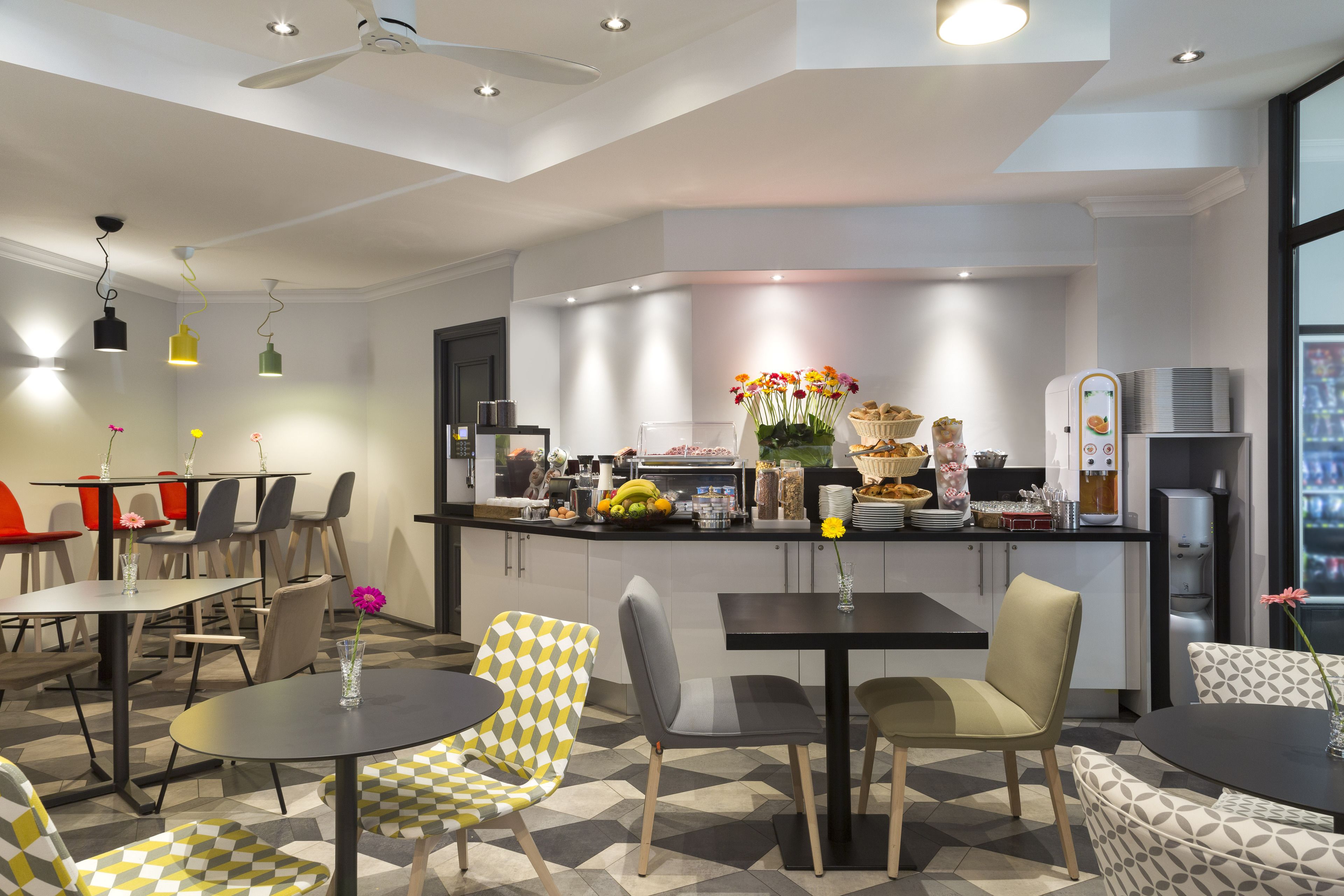 A modern hotel lobby with a central bar area, seating arrangements, and a ceiling fan.