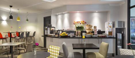 A modern hotel lobby with a central bar area, seating arrangements, and a ceiling fan.