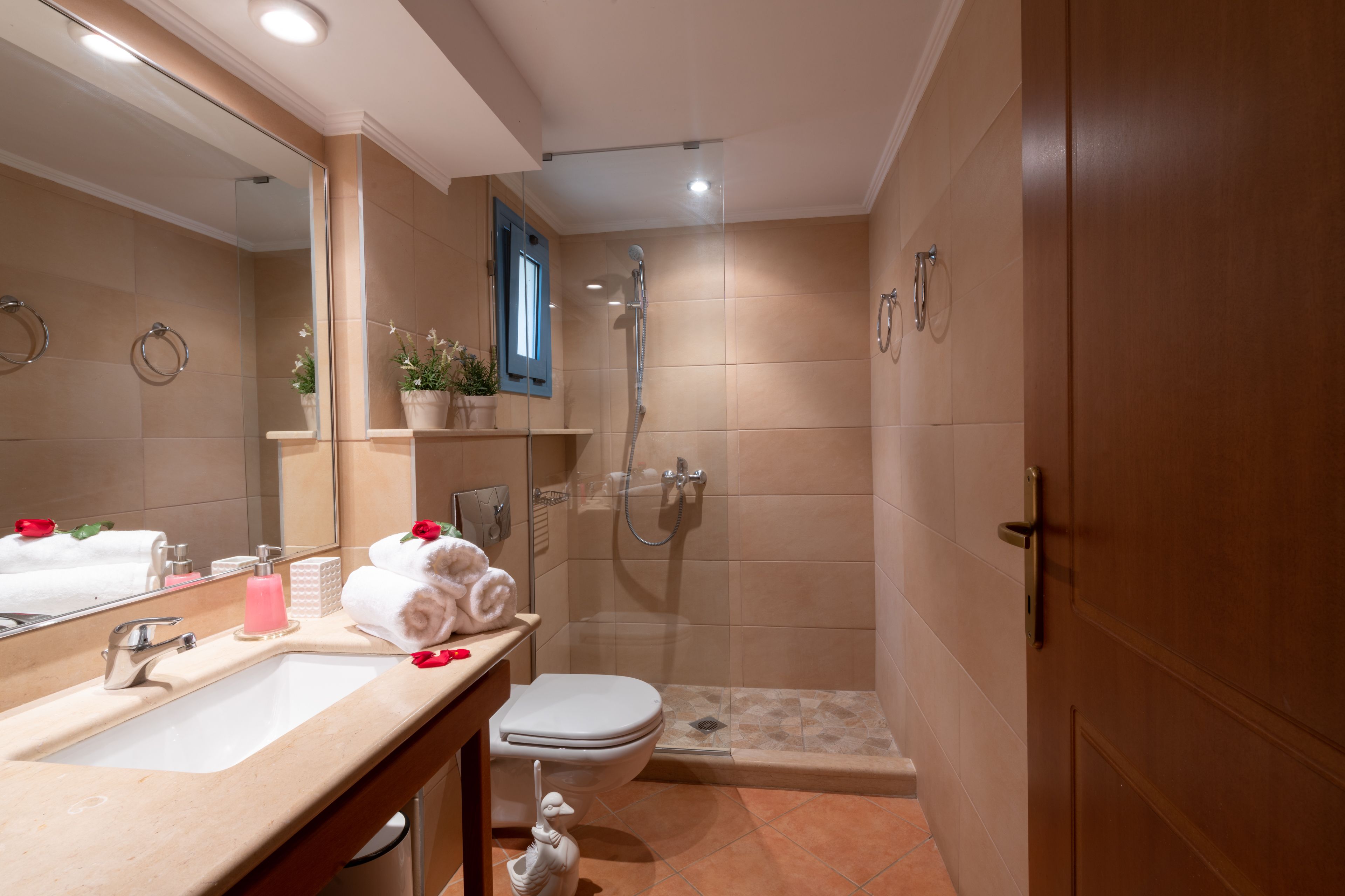 A bathroom with a shower, toilet, sink, and a mirror.