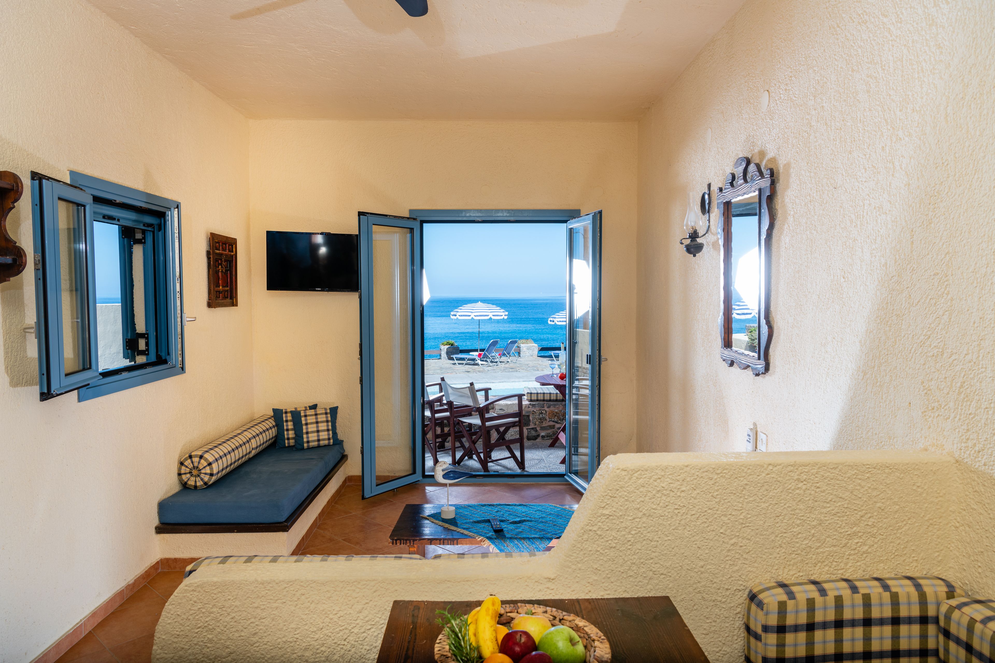 Un salon avec vue sur la mer, un canapé, une table à manger et un téléviseur.