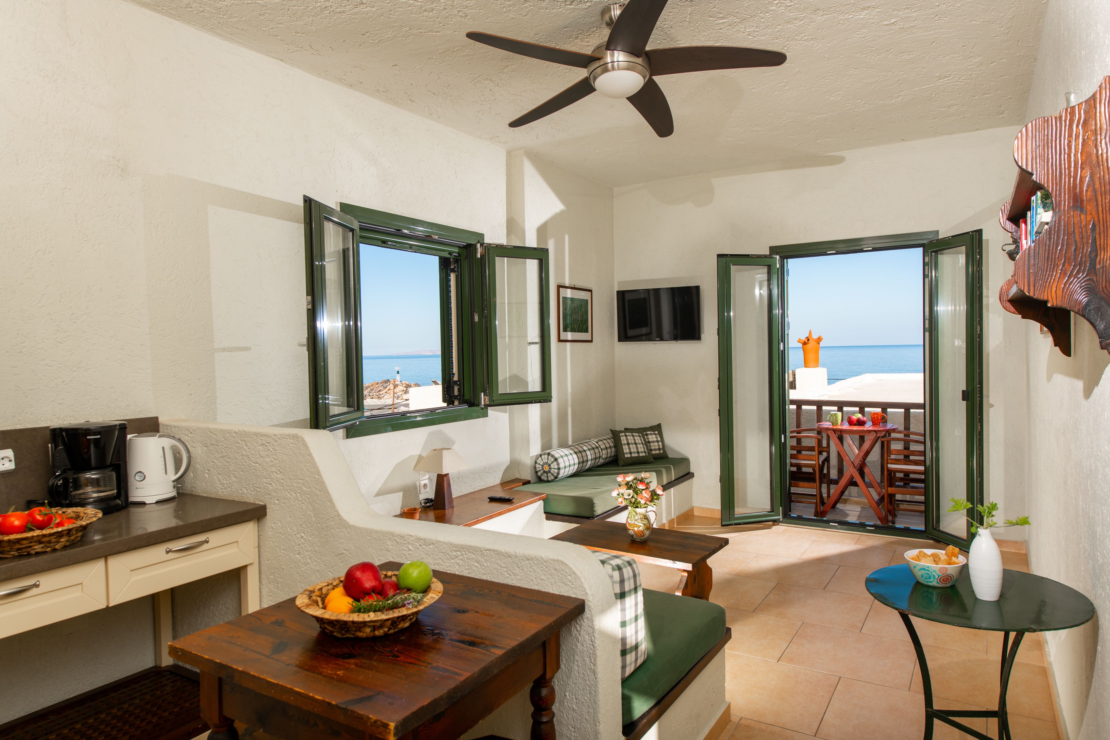 A room with a kitchenette, seating area, and a view of the sea.