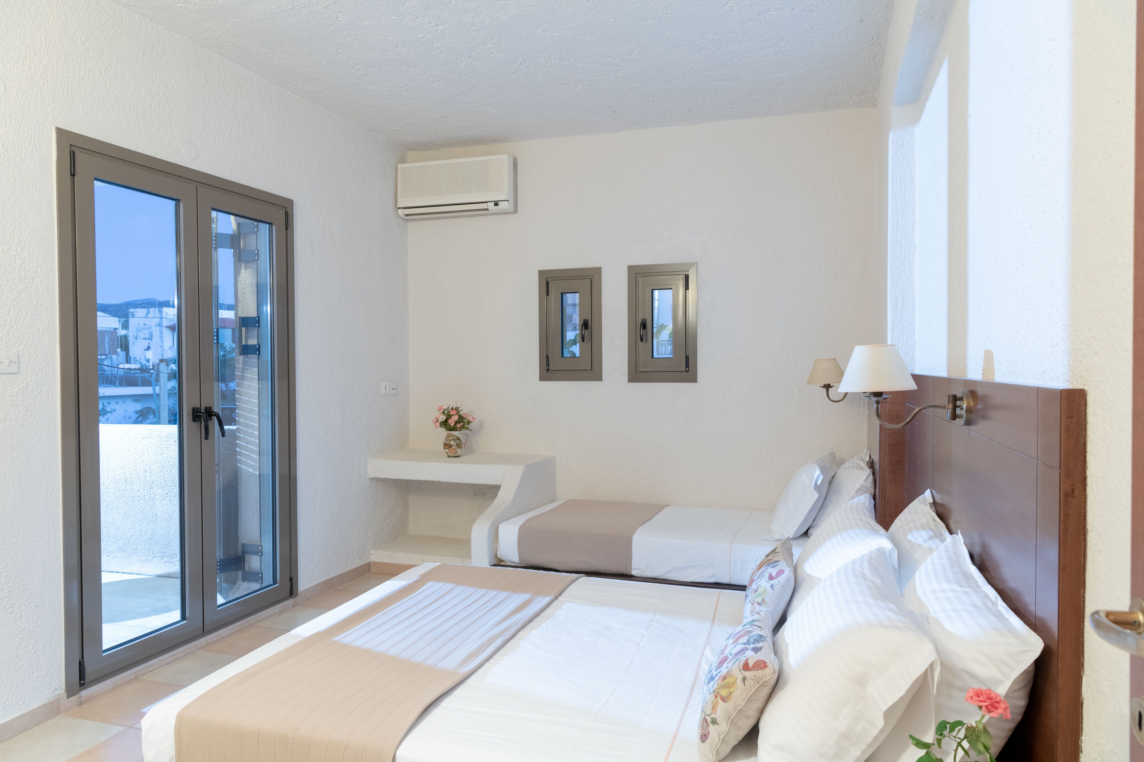 Habitación de hotel con una cama, una mesita de noche, un espejo y una ventana con vistas.