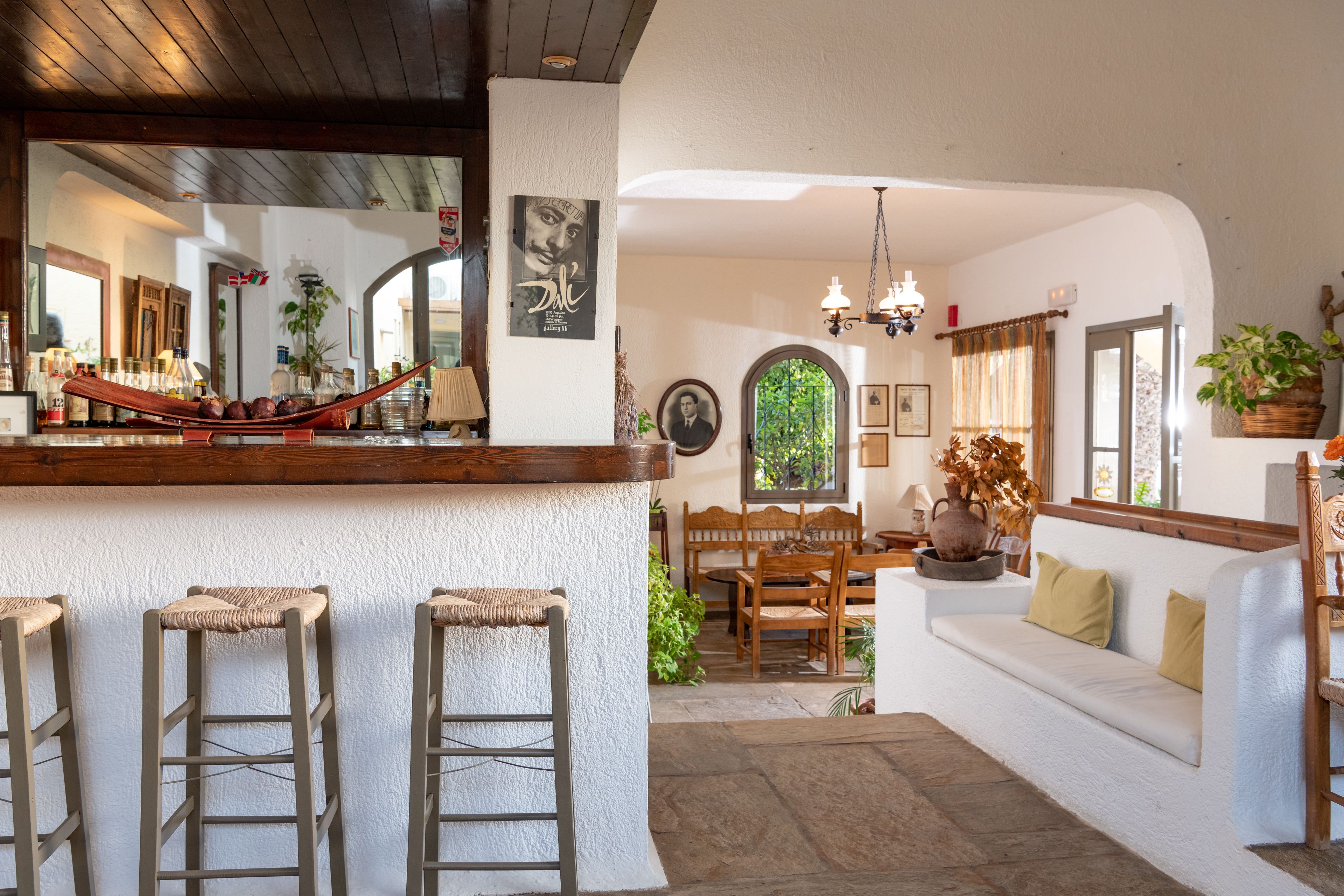 A cozy interior with a bar area, wooden stools, a sofa, and a dining table.