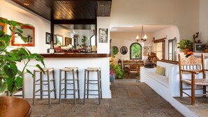 Amplia sala de estar con barra, taburetes de madera, sofá y mesa de comedor.