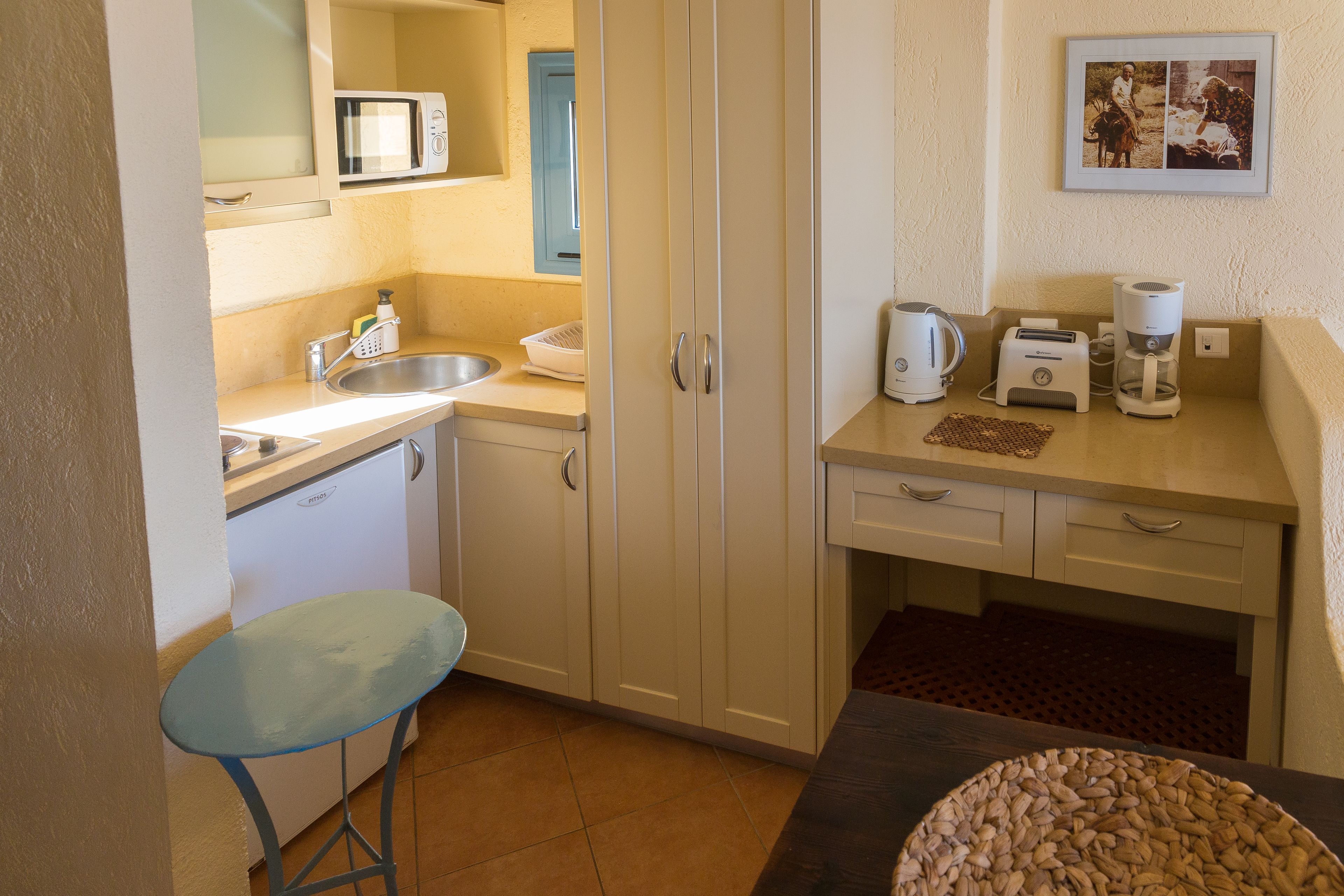 A compact kitchen with a sink, microwave, toaster, and coffee maker.